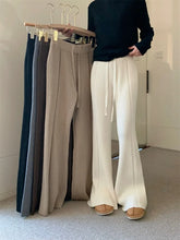 Person wearing white pants with a rack of various pants in the background